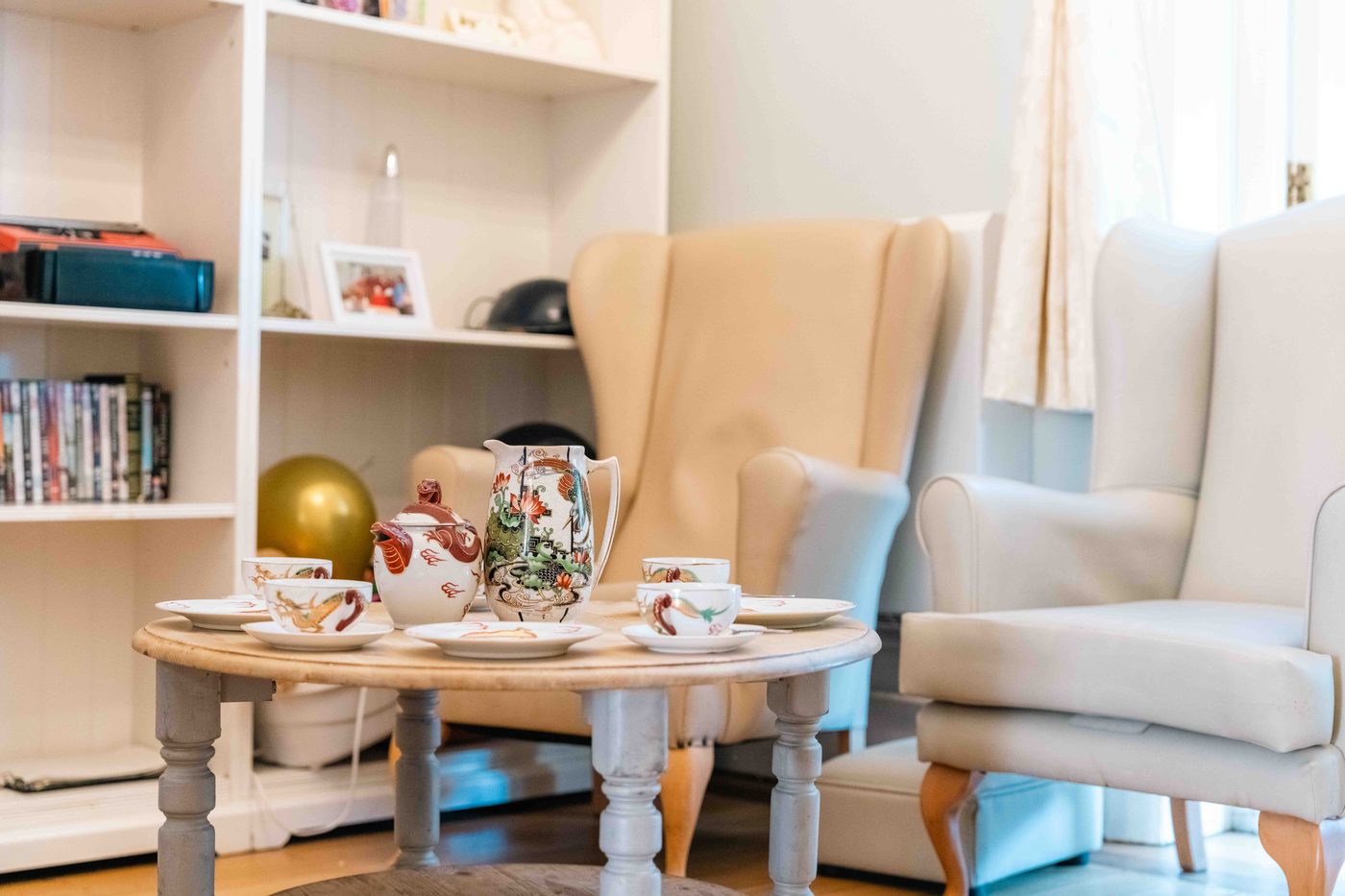 A resident and a carer together in a quiet, sunlit room at Wraysbury House